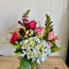 Mixed bouquet of roses, hydrangeas, and snapdragons in a glass vase