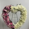 Heart-shaped floral wreath with pink and white flowers on a stand