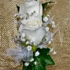 White rose boutonniere with baby's breath and ribbon on a gold background