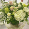 Mixed bouquet of pale roses, hydrangeas, and white calla lilies in a glass vase