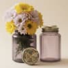 Bright, cheerful daisies tucked into a ribbed purple glass jar make this