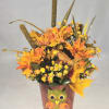 Orange floral arrangement in a painted owl pot with autumn leaves