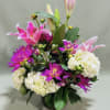 A lush mix of bright pink lilies, vivid magenta daisy-like chrysanthemums, and