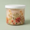 A soft watercolor of daisies and spring blossoms wraps a clear glass