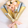 Bouquet of pale pink roses wrapped in blue and gold paper with a pink ribbon
