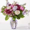Pink, cream, and purple mixed flower arrangement in a lavender glass vase