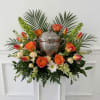 A warm and uplifting urn arrangement featuring vibrant orange roses, tulips, creamy