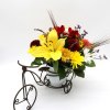 Mixed bouquet with a large yellow lily in a white vase on a decorative tricycle stand