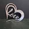 A brushed metal heart-shaped wall hanger that spells out "love" brings a