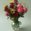 A vivid mix of deep red roses, bright pink peonies and sunny