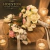 Cream and pink rose bouquets with ribbon on a wooden table beside candles