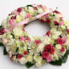 A heart-shaped sympathy wreath in soft pinks, whites, and reds designed to