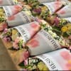 Multiple pastel-wrapped mixed flower bouquets with yellow roses and pink blooms on a wooden table