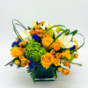 Orange roses and white lilies in a square glass vase