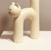 A whimsical cream cat sculpture paired with fresh flowers makes an instantly