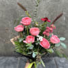 Hand-tied bouquet of pink roses with mixed greenery and small white flowers