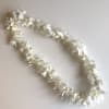 White flower lei on a plain light background