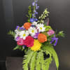A lively mix of bright roses, daisies, carnations and chrysanthemums gives this