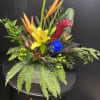 A bright yellow lily and vivid blue rose anchor this tropical bouquet