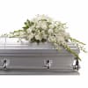 A casket spray made of all white flowers and simple greenery is