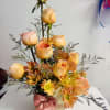 A tall and elegant arrangement featuring orange roses and warm seasonal blooms
