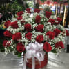 Large red rose arrangement with baby's breath in a round box and white ribbon