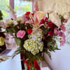 Mixed bouquet of pink and white flowers in a glass vase with a red ribbon