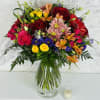 Colorful mixed bouquet in a clear glass vase with roses and daisies
