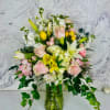 Mixed bouquet of pink roses, white lilies, and yellow flowers in a glass vase