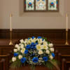 Blue and white floral spray on a wooden casket in a church