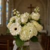 White floral arrangement in a glass vase with a ribbon