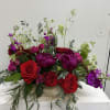 Saturated red roses and deep purple blooms create a bold, romantic statement