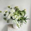 White floral arrangement in a ribbed white vase