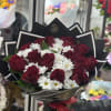 Bouquet of red roses and white daisies wrapped in black paper