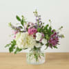 Mixed pink, white, and purple flowers in a clear glass vase