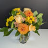 Bouquet of yellow and peach flowers in a clear glass vase