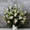 White floral arrangement in a white vase with lilies and roses