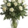 A cluster of soft ivory roses set among abundant mixed greenery creates