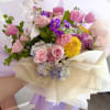Bouquet of pink roses, tulips, orchids, and yellow mums wrapped in cream paper