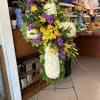 Standing floral cross with white chrysanthemums, yellow roses, and purple flowers