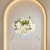 A cloud of white roses, hydrangeas &amp; lisianthus in a clear vase