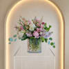 A loaded arrangement with fresh flowers in a stunning pink ribbed glass