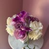 A compact cluster of blush and ivory roses paired with vivid purple