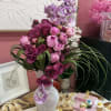 Rich plum roses and spotted purple Phalaenopsis orchids mingle with soft pink