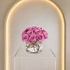 Pink roses arranged in a low clear glass vase in a compact