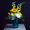 Yellow sunflowers and white blooms in a blue glass vase