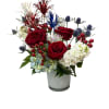 Red roses and white hydrangeas in a glass vase with decorative picks