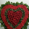 Heart-shaped red rose arrangement with red carnations and green foliage