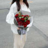 Velvety red roses framed by soft greenery, wrapped in sleek gray paper