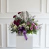 Low sympathy arrangement with Angel statue surrounded by lush blooms in white